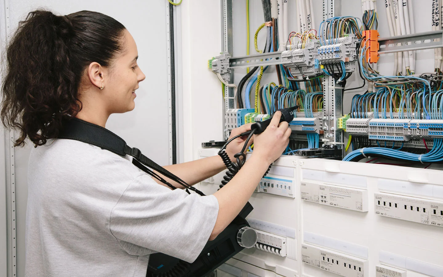 E-CHECK - Mitarbeiterin prüft im Schaltschrank mit einem Meßgerät &middot; Hornetz